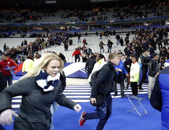 Spectators invade the pitch of the Stade de France stadium after the international friendly soccer match between France and Germany in Saint Denis, outside Paris, Friday, Nov. 13, 2015. Hundreds of people spilled onto the field of the Stade de France stadium after explosions were heard nearby during a friendly match between the French and German national soccer teams. French President Francois Hollande says he is closing the country's borders and declaring a state of emergency after several dozen people were killed in a series of unprecedented terrorist attacks. (AP Photo/Christophe Ena)