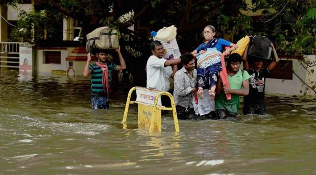 Chennai: An older woman lifted by rescue worker following heavy rains, in Chennai on Monday. PTI Photo(PTI11_16_2015_000203B)